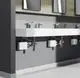 Mehrere moderne Wasserhähne an einer langen, weißen Waschbeckenoberfläche mit unterirdisch montierten Mini-Durchlauferhitzern von Stiebel Eltron in funktionalem Design.